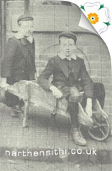 2 boys plaing in a wheelbarrow